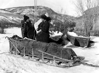 “The Policeman takes over the mail sack.” Constable Joe Kessler of the RCMP relieves DeWolfe of the mail at Forty Mile in 1938.
