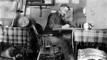 “The scene of many pleasant hours' work.” Not all of Claude's duties took place outdoors; there was also paperwork to do! Here at the RNWMP post in New Rampart House, the banjo is evidence of Claude's musical interests.
