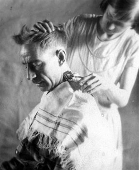 Mary coupe les cheveux de Claude. Comme bien des photos de Claude prises à l'intérieur, cette imagine est d'une intimité inhabituelle. 