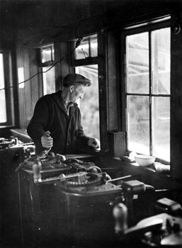 Winchman Hans Oiom turning a crack in the winchroom at Yukon Consolidated Gold Company (YCGC) dredge #3 in Dawson, 1938.