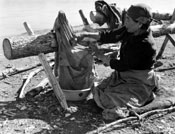 Liza Steamboat scrapes a caribou skin.